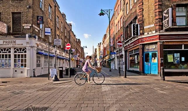 A cyclist on the brick-paved street of Brick Lane