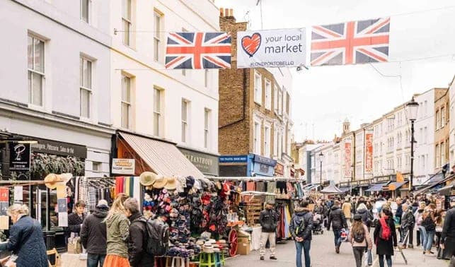 Busy market stalls along Portobello Road beneath Union Jack flags