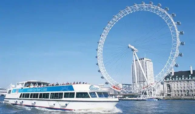 A river cruise boat on the Thames in front of the London Eye