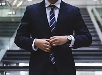 A chauffeur in a dark suit adjusting his cufflinks